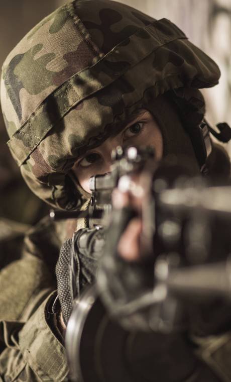 Close shot of a masked soldier in helmet pointing a gun